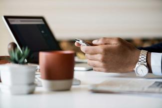 Hands at a coffee table with laptop.